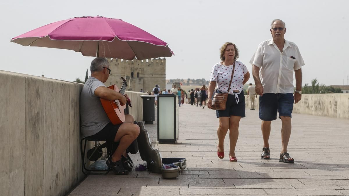 Un músico callejero se protege del sol en el Puente Romano