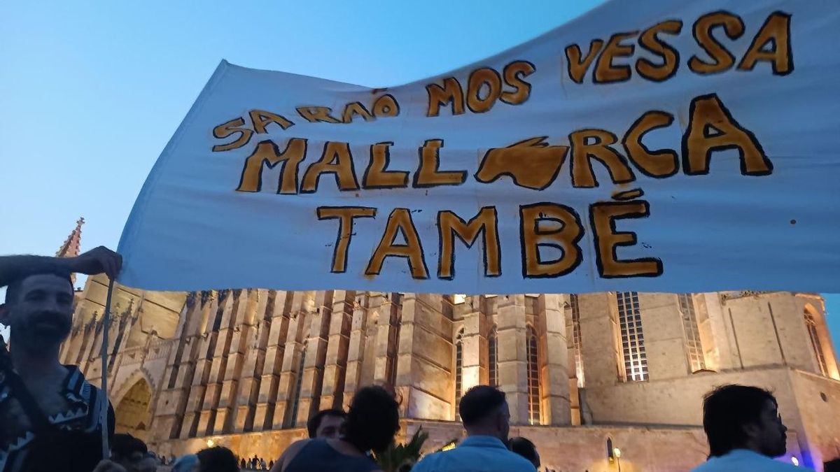 Un manifestant sosté una pancarta davant la Catedral de Palma amb el lema en català "Sa raó mos vessa, Mallorca també"