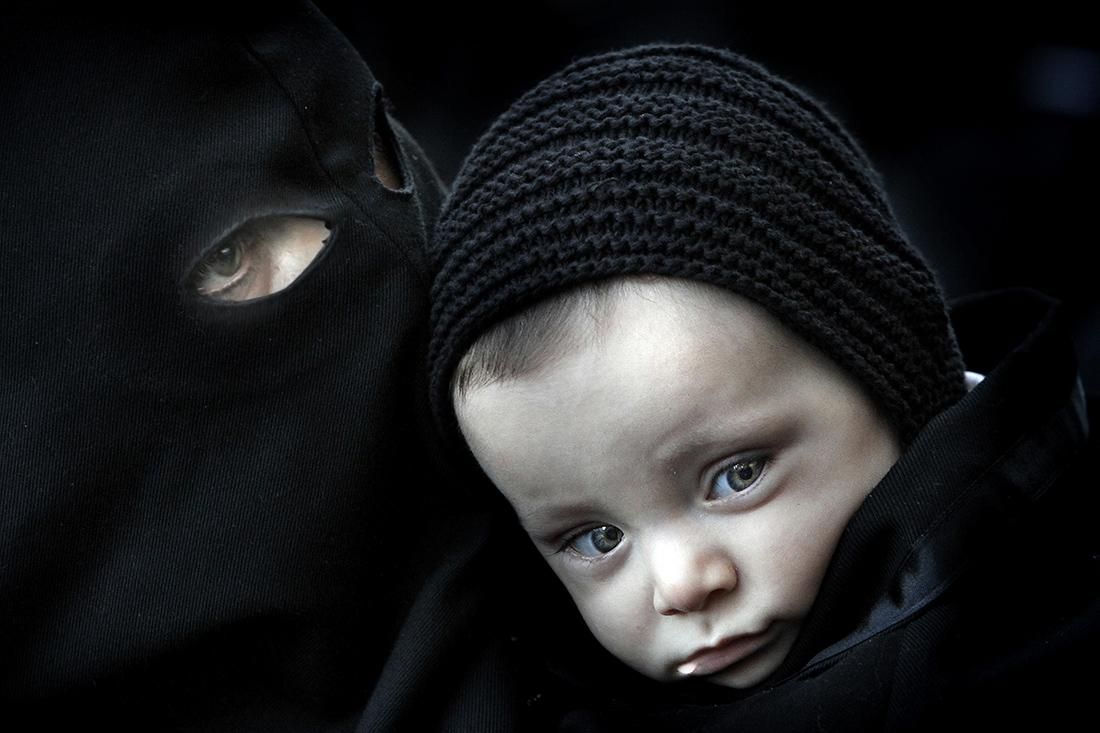 Un penitente con su hijo durante el pregón de las bienaventuranzas en la plaza de la Catedral de León, durante la celebración de la Semana Santa. | BRUNO MORENO (15/04/2014)