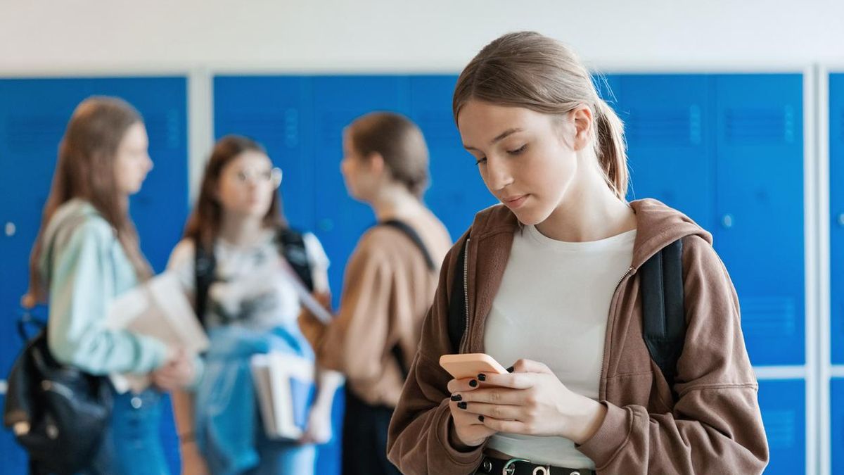 Adolescente con un teléfono móvil en el instituto
