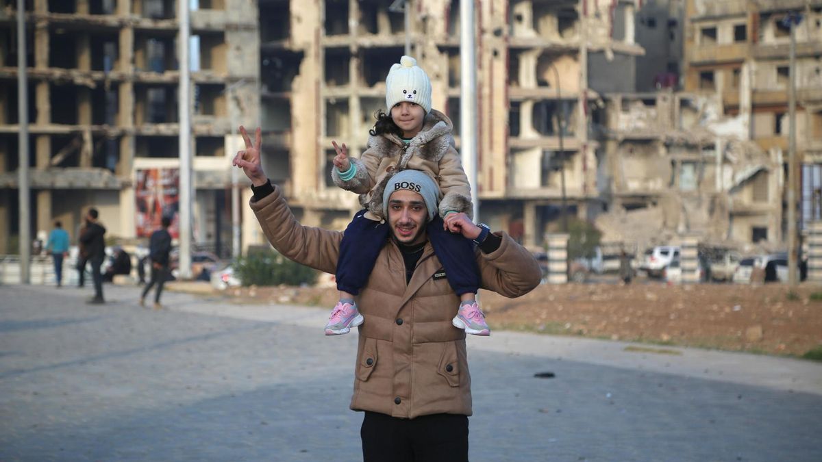 Un hombre celebra junto a su hija la captura de Damasco y la caída del régimen de Al Asad en la ciudad de Homs.