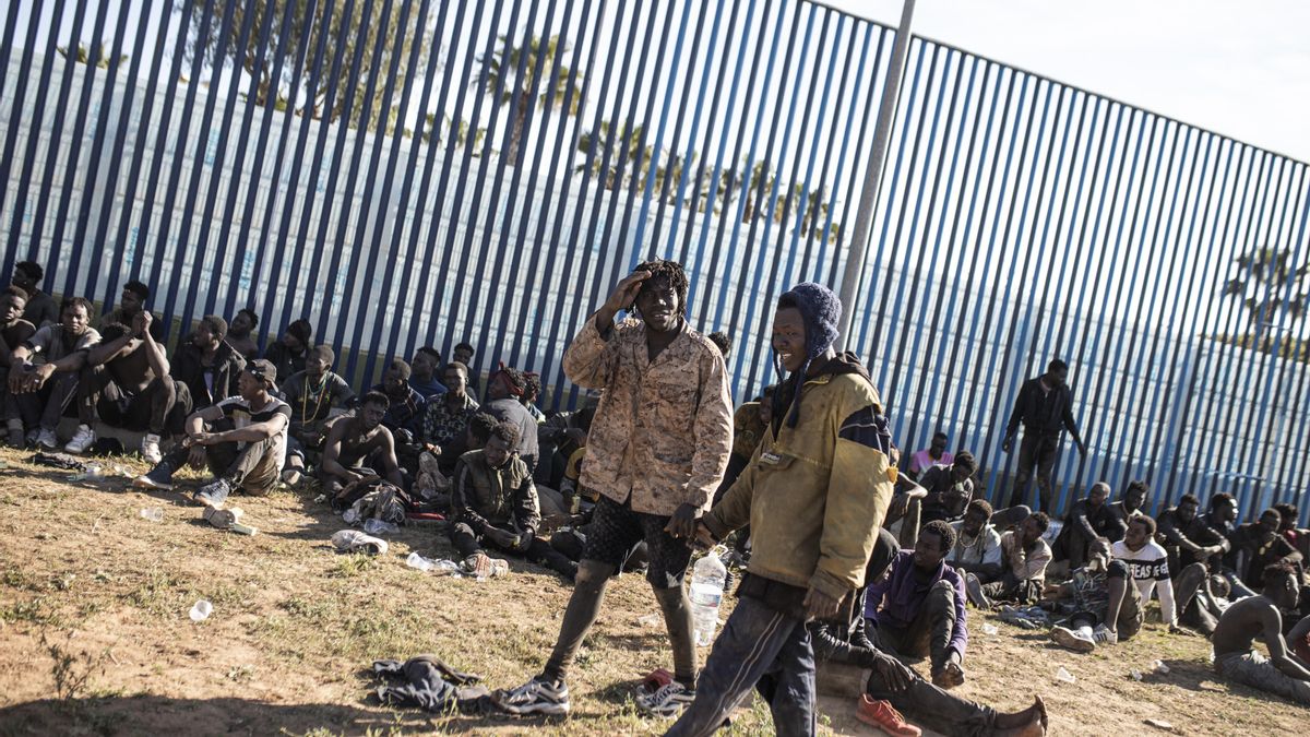 Archivo - Varios migrantes son atendidos por personal sanitario tras saltar la de Melilla el pasado 2 de marzo