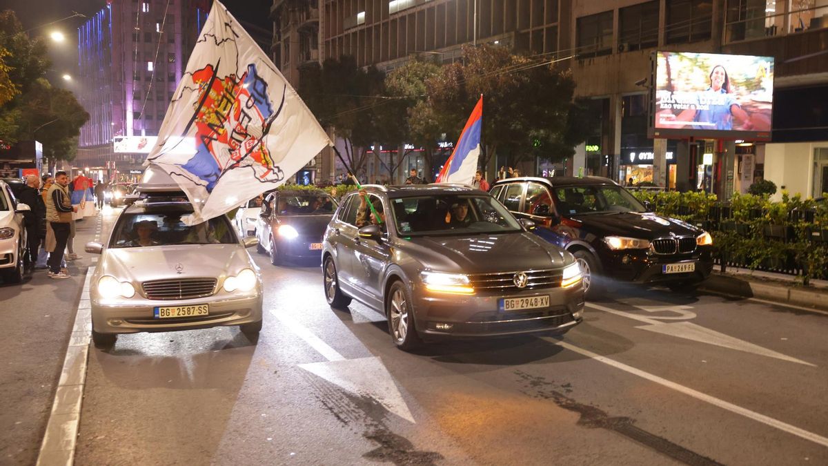 Varias personas con banderas de Serbia apoyan la victoria de los estudiantes en sus coches este domingo en Belgrado.