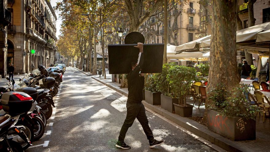 Un camaerero monta una terraza en las Ramblas de Barcelona, con limitaciones de aforo y horario. EFE/Enric Fontcuberta