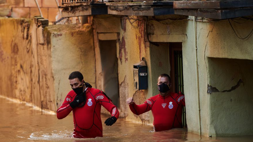 Trabajadores de Protección Civil caminan por una calle inundada, a 12 de diciembre de 2021, en Tudela.