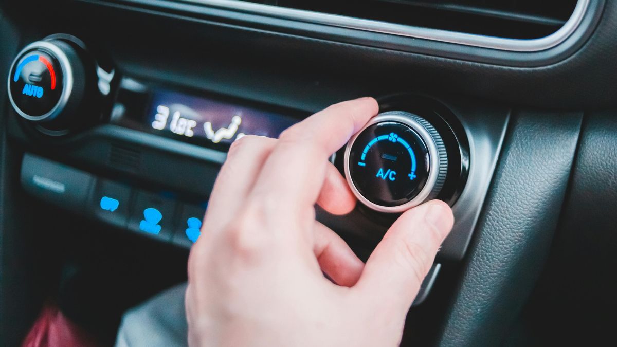 Una persona ajustando la temperatura del aire acondicionado