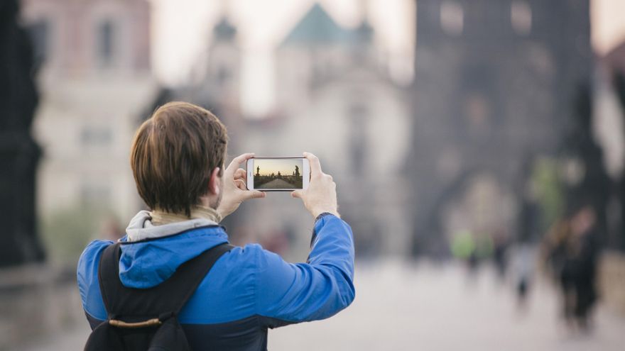 Una turista fotografía el Puente de Carlos en Praga con su smartphone