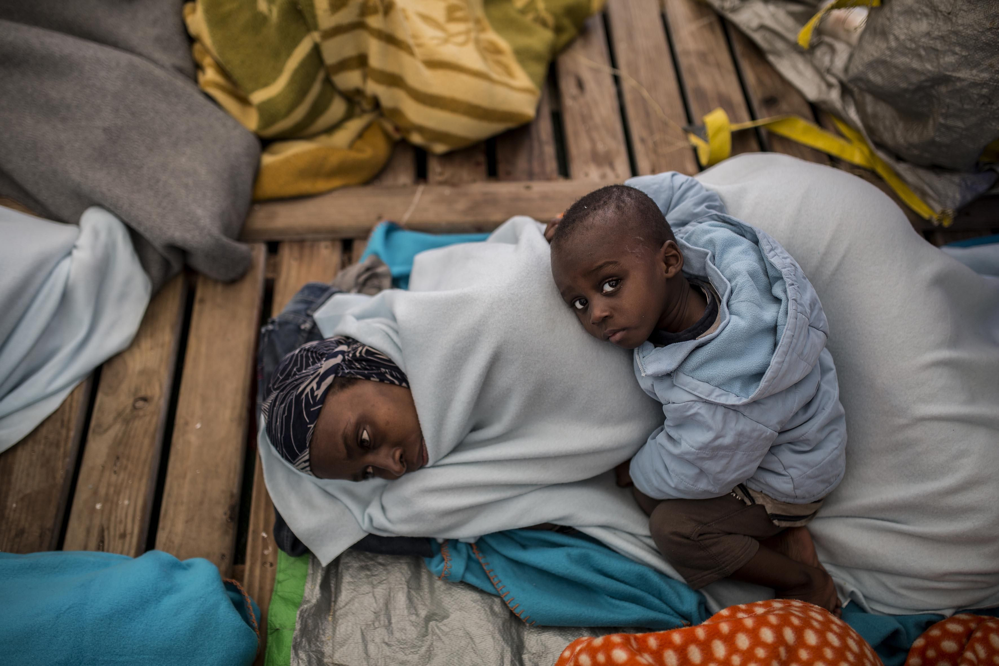 Fanta Diaby y su hijo Moustafa Diaby, de 1 año y 11 meses, procedentes de Costa de Marfil, se protegen del frío con una manta en la cubierta del barco Open Arms / Olmo Calvo