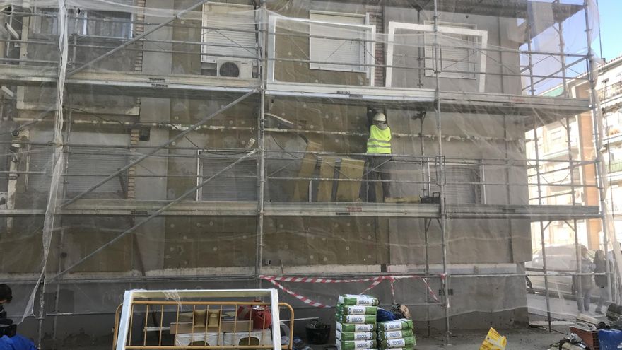 Operarios trabajan subidos a un andamio.