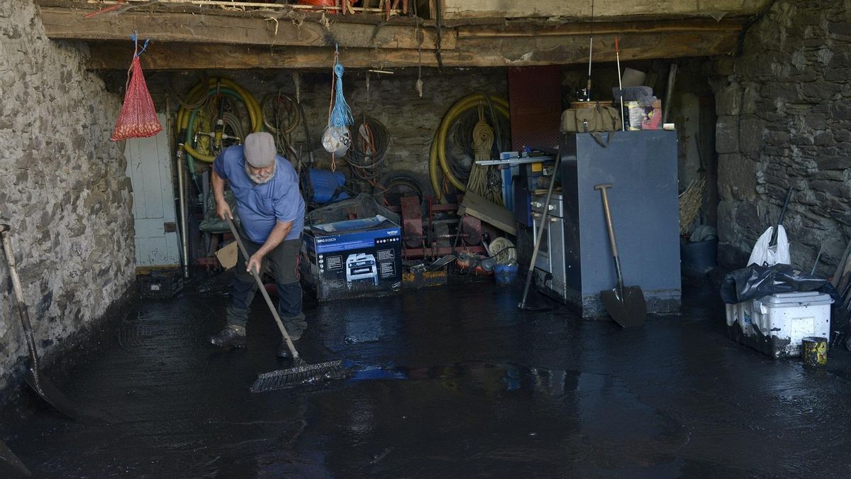 Un vecino limpia un bajo que se inundó en Pradocabalos (Viana do Bolo, Ourense) con las fuertes tormentas.