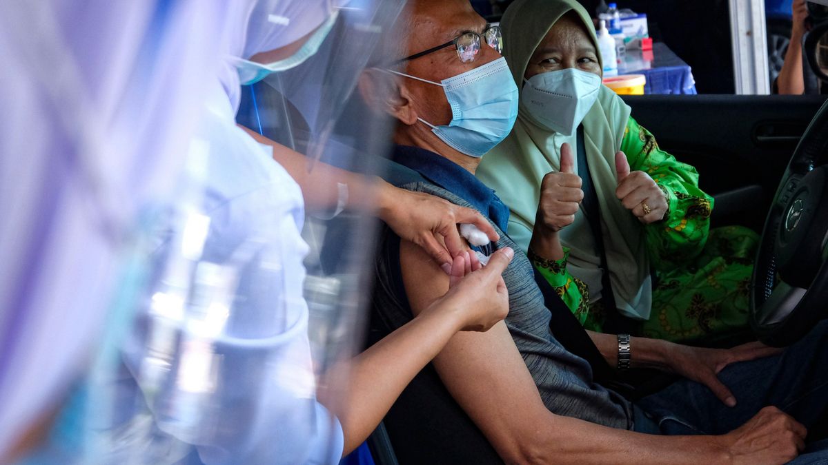 Un hombre recibiendo la vacuna contra el coronavirus en su coche en Malasia.