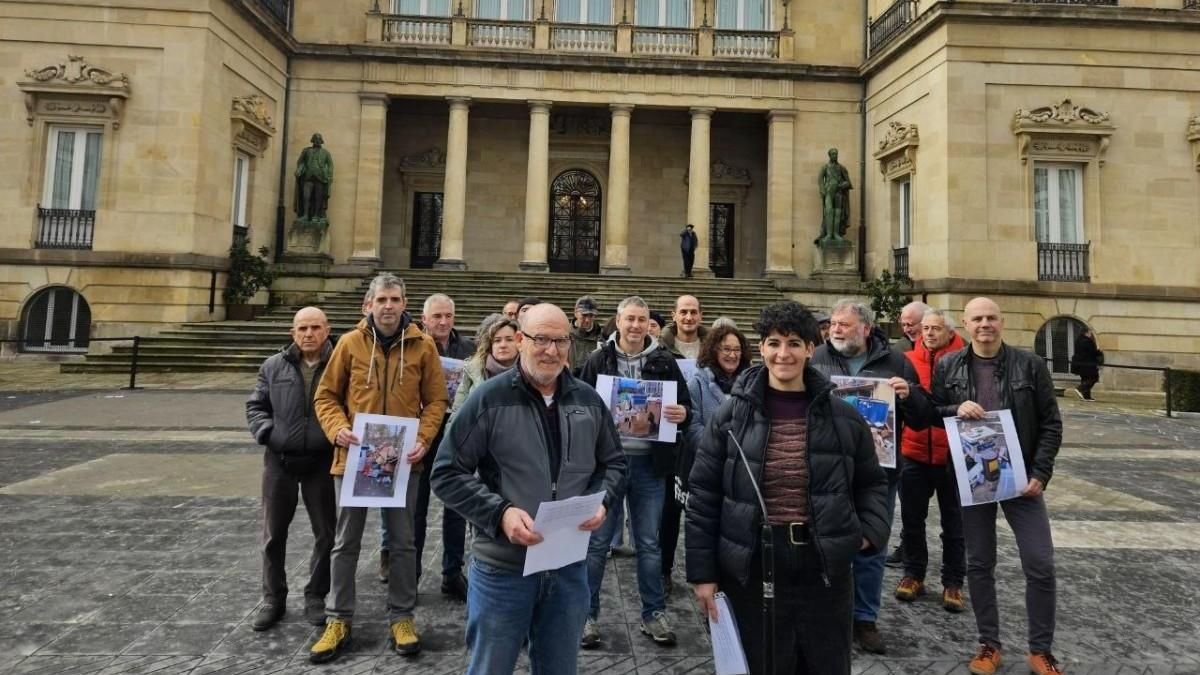 Alcaldes de municipios alaveses, concentrados ante el palacio de la Diputación, con carteles en los que se muestran papel y cartón acumulados en los contenedores