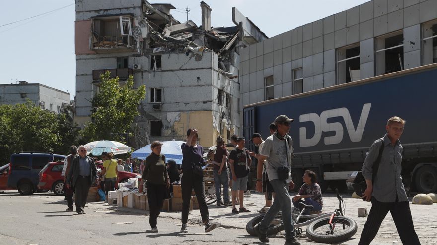 Personas caminan junto a un edificio destruido en Mariúpol.