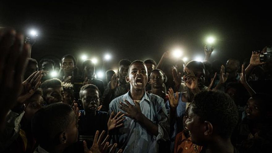 El fotógrafo japonés Yasuyoshi Chiba ha sido galardonado este jueves con el World Press Photo por su fotografía del grito pacífico de un grupo de jóvenes en Sudán, que iluminaban con sus teléfonos móviles a un chico mientras recitaba un poema.