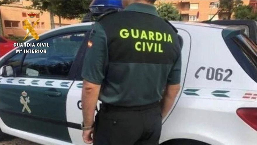 Archivo - Un agente de la Guardia Civil junto a su vehículo.