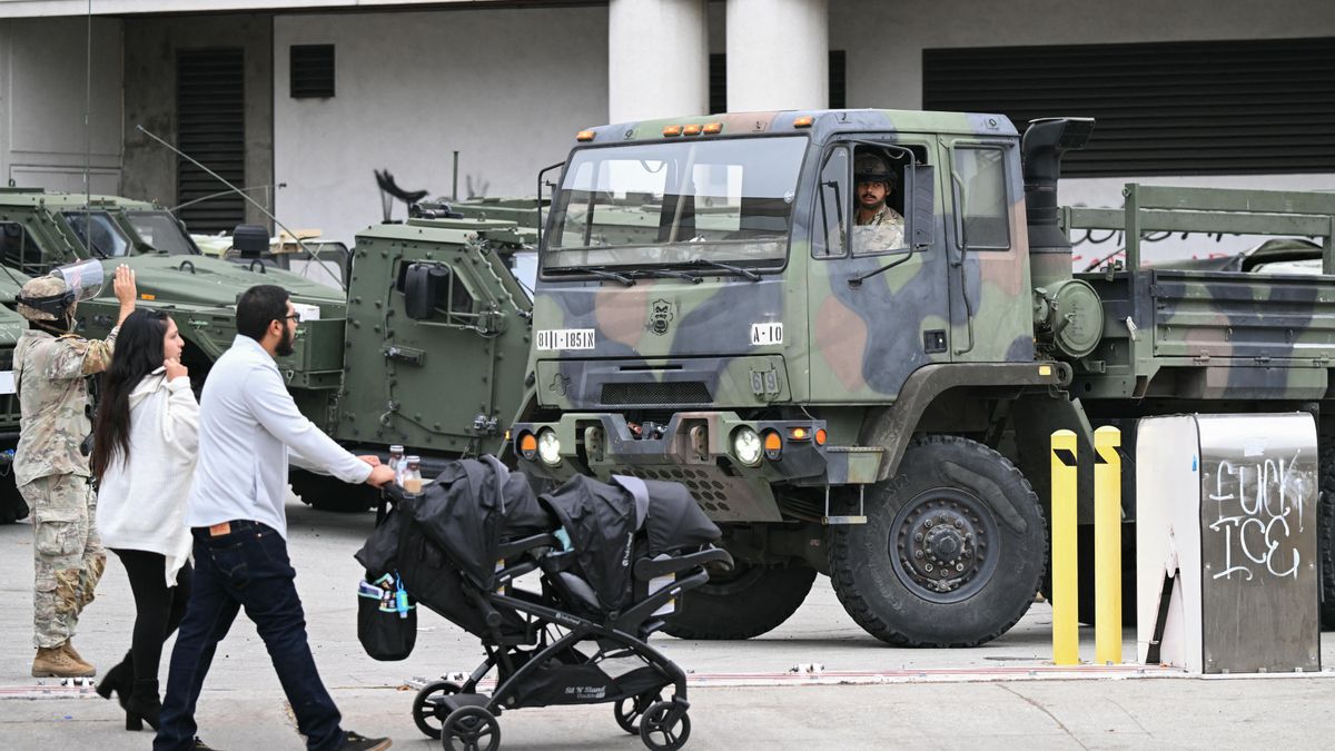 Una pareja empuja un cochecito de de bebé mientras miembros de la Guardia Nacional de California montan guardia frente al edificio federal Edward R. Roybal en la mañana del 10 de junio de 2025, en Los Ángeles.