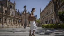Una mujer con mascarilla y guantes caminando por una calle de Sevilla durante la fase 2.