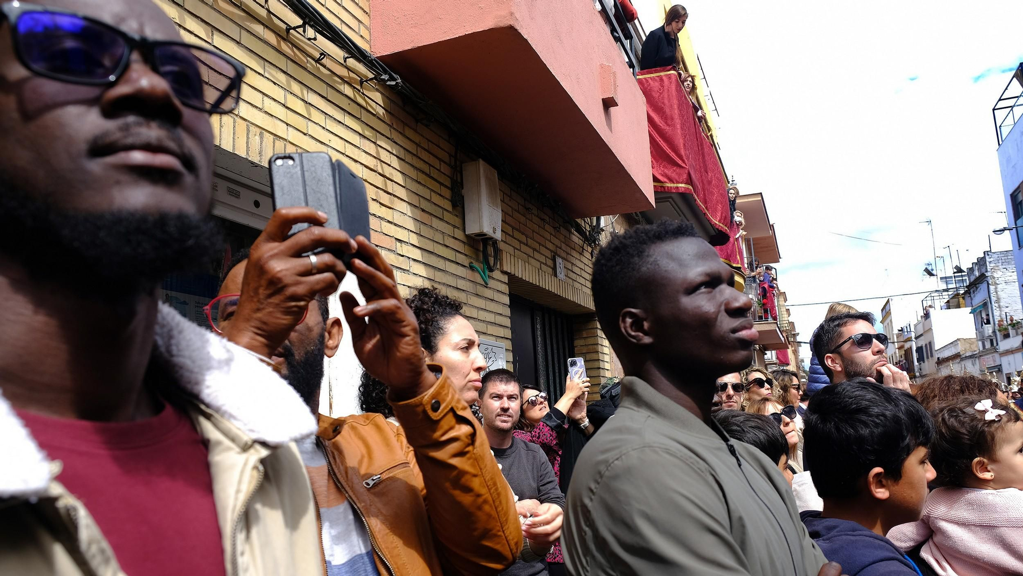 Los vecinos del Cerro del Águila, un barrio multicultural, se unen al paso de su hermandad (puerta de la Fundación Conviven)
