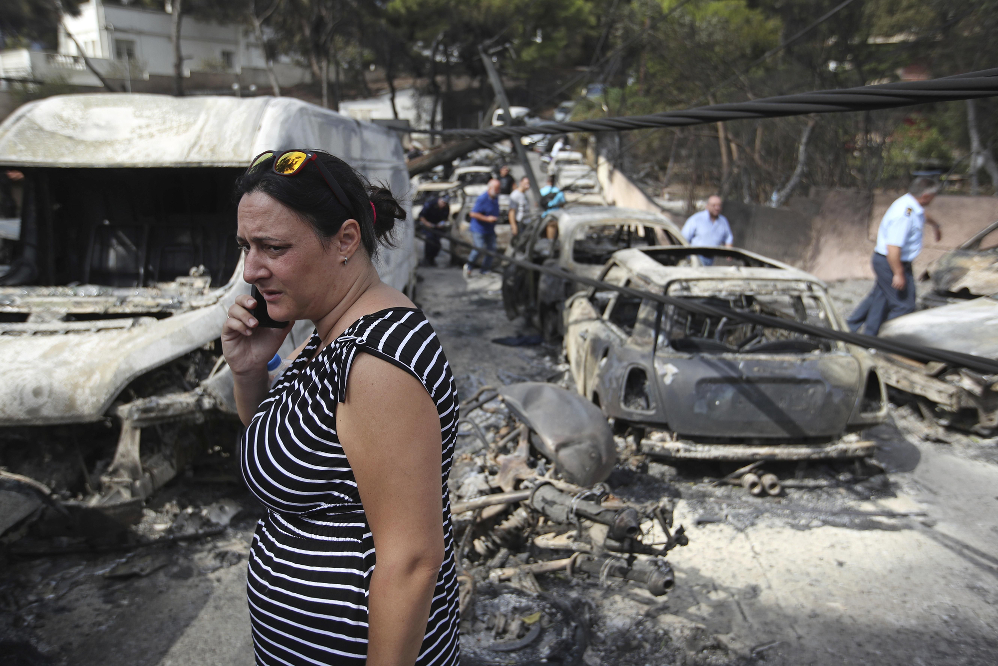 Una mujer habla por teléfono en medio de varios coches quemados en Mati, al este de la capital griega