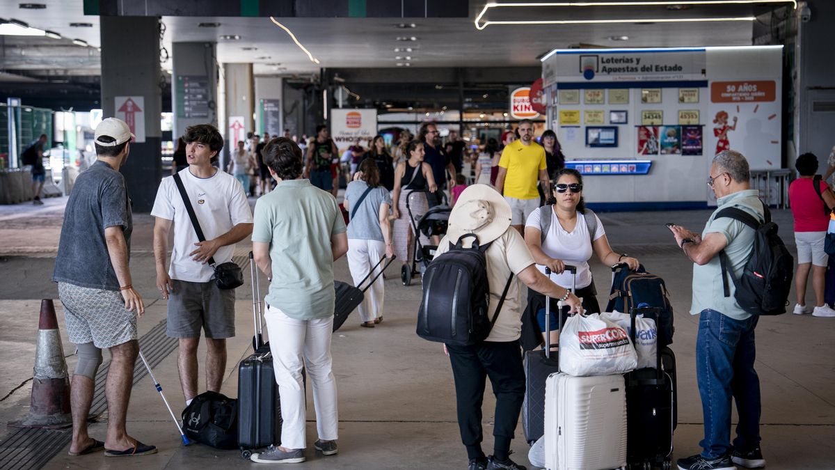 Varias personas esperan con maletas y observan los carteles de salidas, en la estación de Chamartín Clara Campoamor, en Madrid.