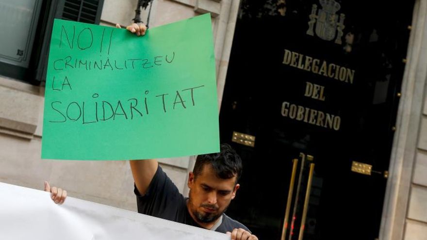 Un ciudadano porta una pancartas con el mensaje 'No criminalicemos la solidaridad', durante la concentración que tuvo lugar este lunes frente a la Delegación de Gobierno en Cataluña convocada por la Coordinadora Obrint Fronteres y Stop Mare Mortum para exigir una respuesta de los gobiernos español y europeo a la situación de las más de 400 personas rescatadas por el Open Arms y el Ocean Viking en 12 días, y, además, exigir a España un puerto seguro para 31 menores que se encuentran a bordo del Open Arms.