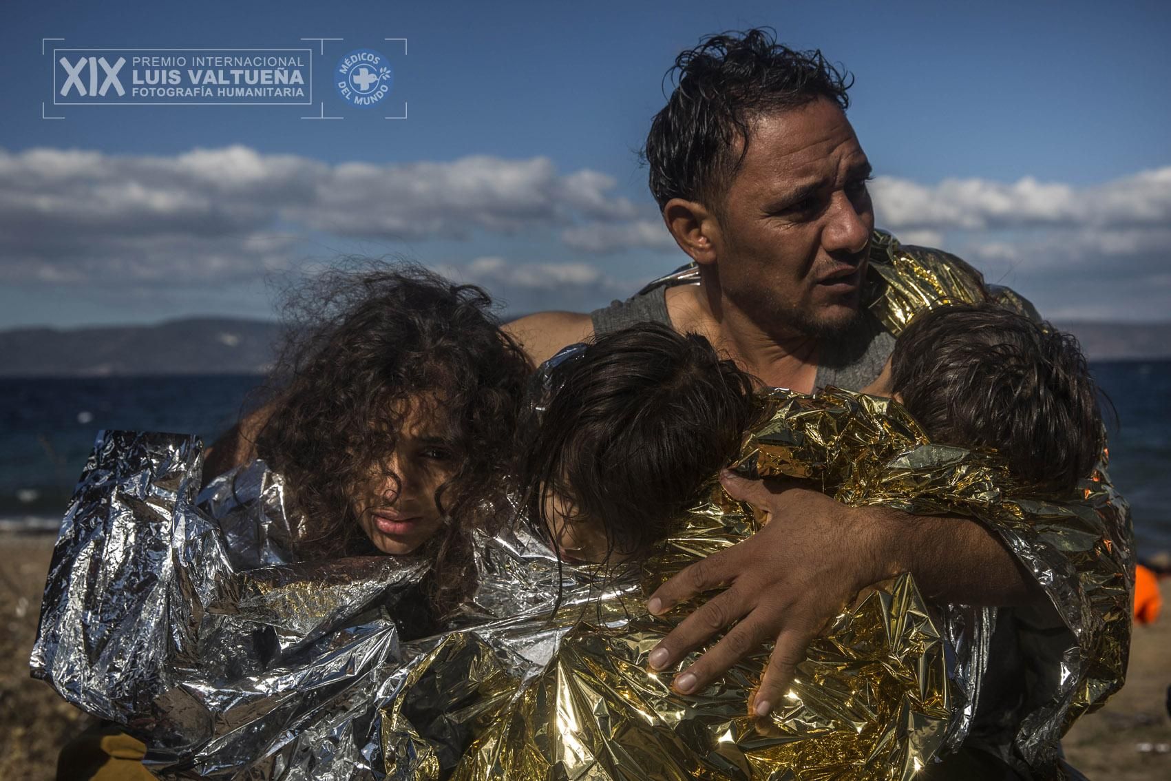 Un padre abraza a sus dos hijas y a su hijo, envueltos en mantas térmicas, justo después de desembarcar en una playa de la isla griega de Lesbos. Al menos 3.770 personas murieron intentando llegar a Europa por el Mediterráneo el pasado año. | Foto: Santi Palacios.