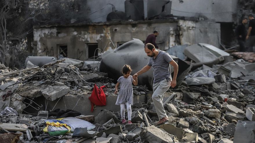 23 October 2023, Palestinian Territories, Gaza City: A Palestinian and a child inspect the destruction caused by an Israeli strike.