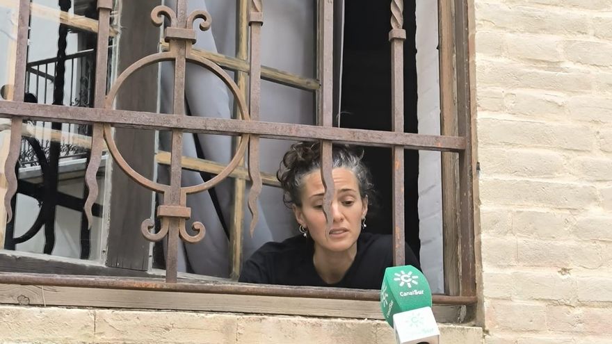 Una de las artesanas atiende a los medios de comunicación desde el interior de la Fábrica de Sombreros mientras mantienen cerrada la instalación.