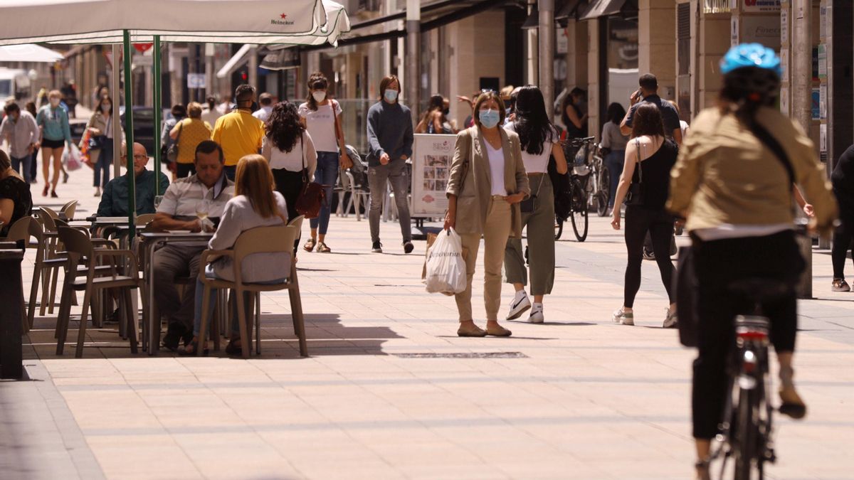 Personas paseando con mascarillas y sentadas en terrazas en una céntrica calle.