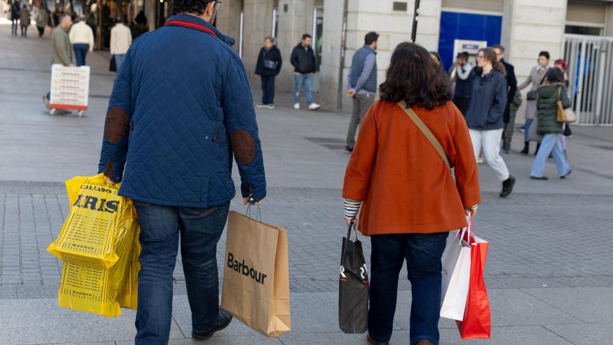 Archivo - Dos personas llevando varias bolsas de compra de distintos comercios