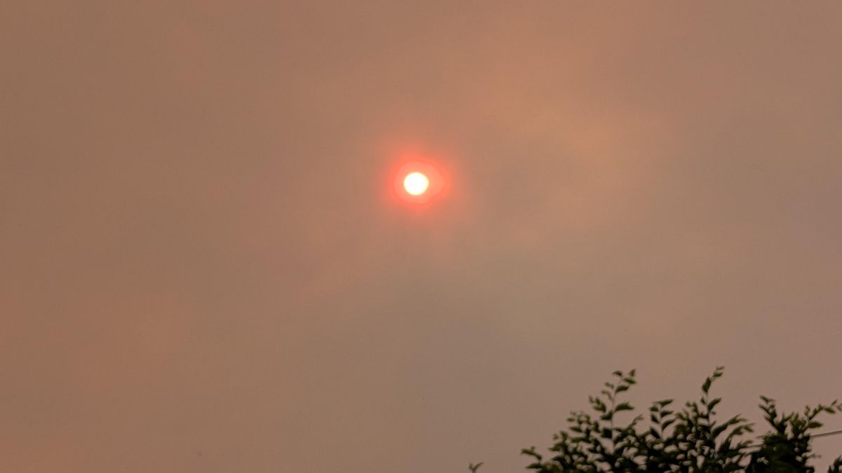 Vista del sol detrás de una nube de humo en la sierra, este jueves