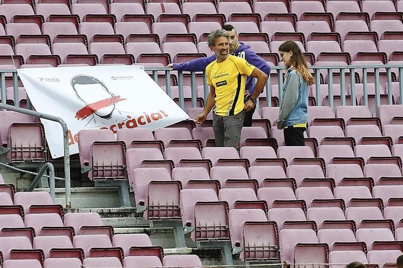 res espectadores en las gradas del Camp Nou con una pancarta. EFE/Alejandro García