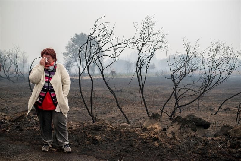 Una mujer llora ante el paisaje calcinado por el fuego, en la zona de Abelenda das Penas (Carballeda de Avia). EFE
