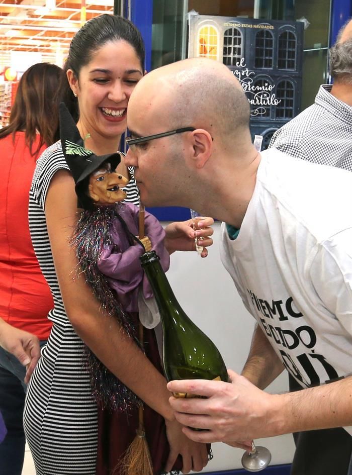 l gerente de la Administración de Lotería número 8 de Telde "La Brujita", Alberto Suárez, da un beso a la muñeca de la brujita que habitualmente preside su establecimiento