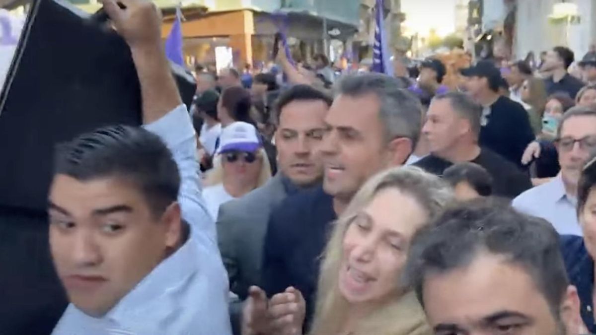 Un custodio despliega el maletín de seguridad frente a Karina Milei y Menem, este jueves, en el centro de Corrientes.