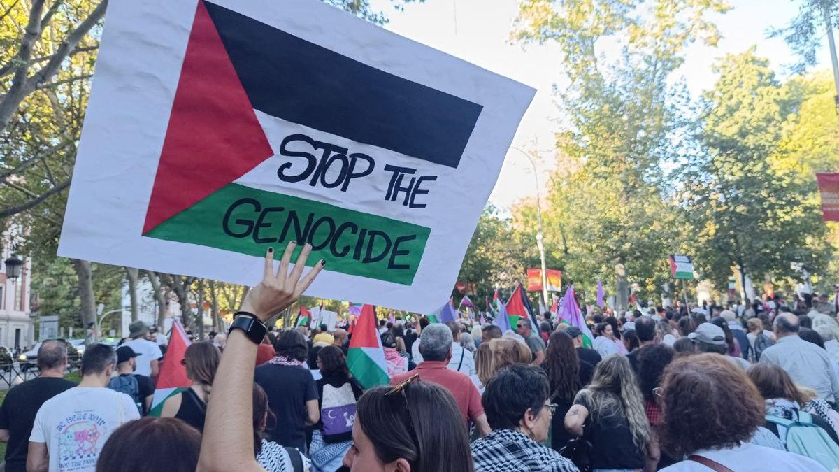 A young woman with a banner with the Palestine flag in which she asks for the end of the genocide in the demonstration of Madrid.