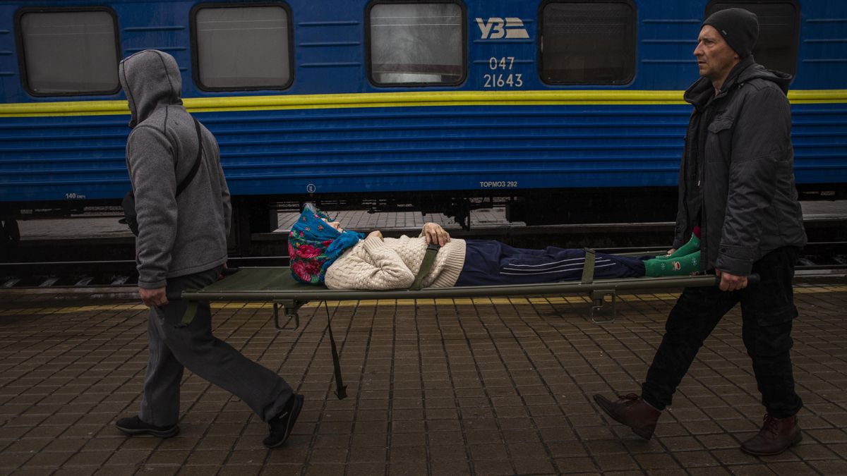 Personas transportando a una mujer en camilla hasta un tren en la estación en Pokrovsk.