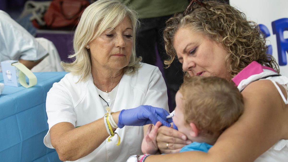 Una enfermera administra una vacuna intranasal a un niño en un colegio.