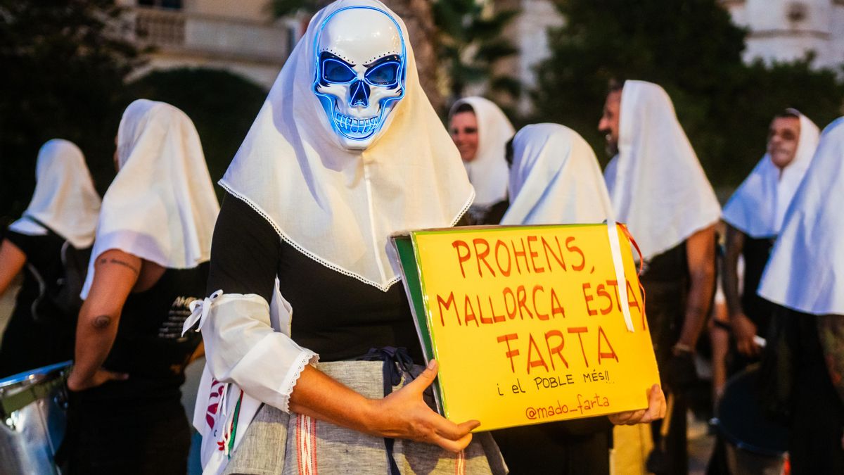 L'activista posa amb la pancarta dirigida a la presidenta del Govern, Marga Prohens (PP), on pot llegir-se: "Mallorca està farta".