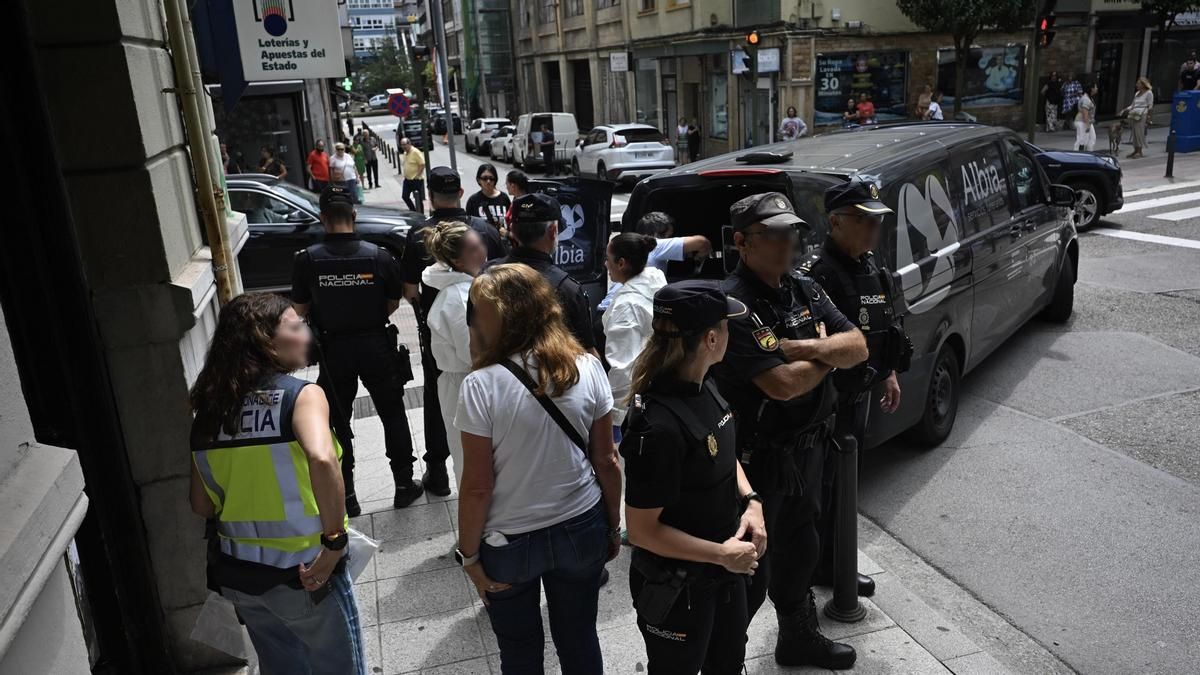 La policía custodia la entrada del piso de Perines mientras la funeraria saca el cuerpo de la víctima, de 27 años.