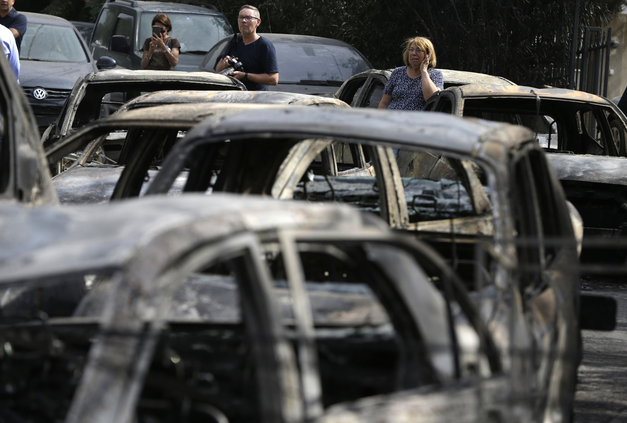 Varias personas observan los coches quemados en la localidad de Mati, situada al este de Atenas