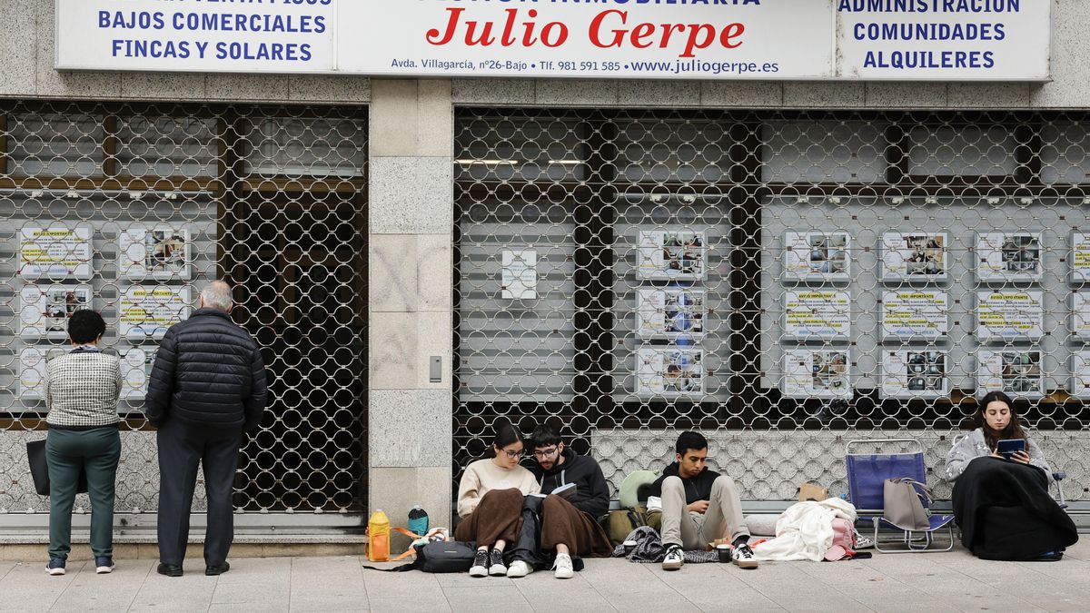 Un grupo de jóvenes espera la apertura de una inmobiliaria en el barrio de Conxo (Santiago de Compostela)