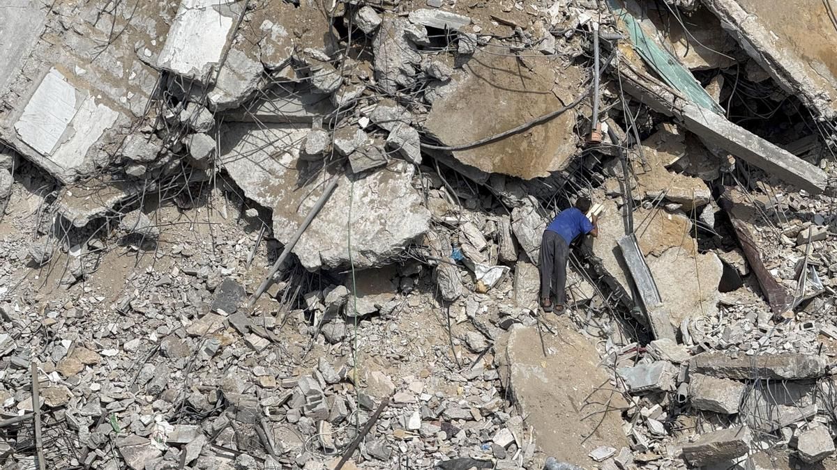 Un joven palestino intenta salvar este lunes algunas de sus pertenencias entre los escombros de la torre Al Jundi, en la ciudad de Gaza