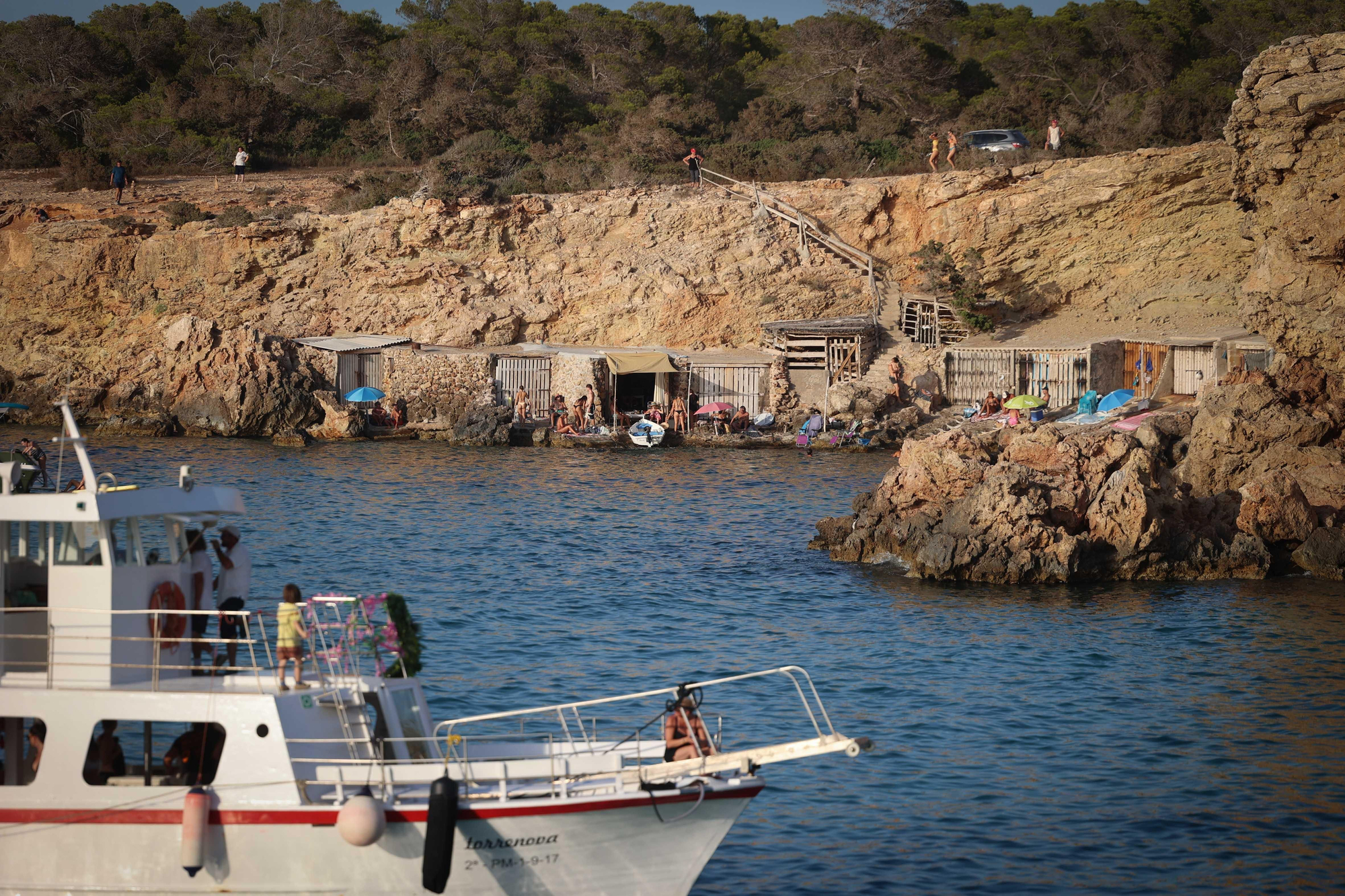 Las casetas de pescadores y los embarcaderos tradicionales de Cala Comte se convierten en un mirador para decenas de espectadores