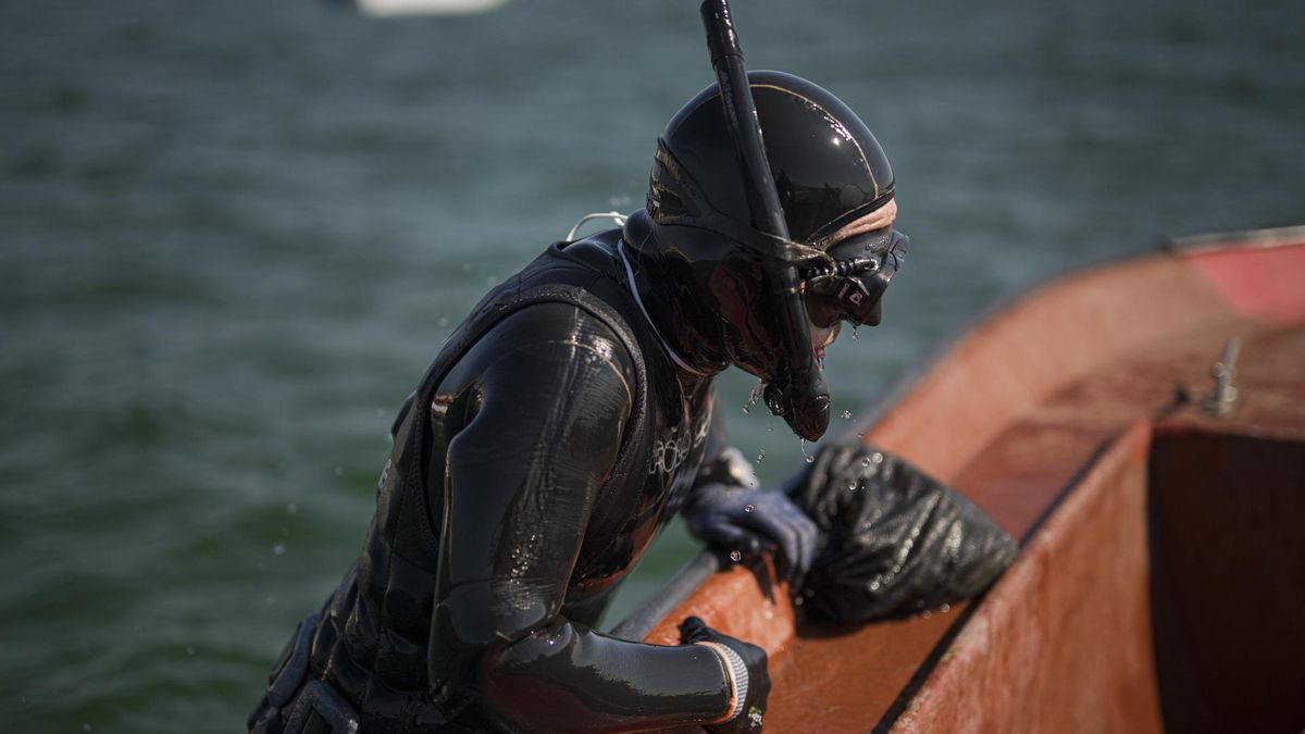 Uno de los buceadores retorna a la embarcación para vaciar la bolsa en la que va guardando las navajas que recoge en el fondo