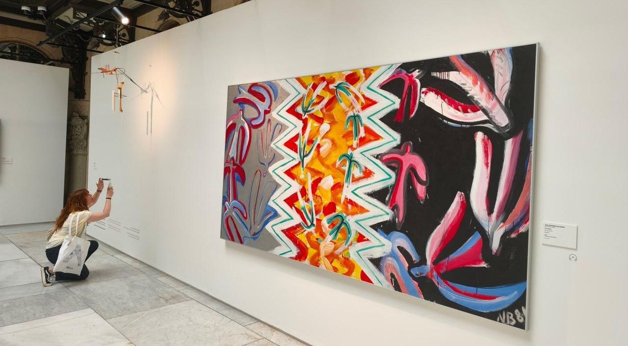Una visitante fotografía la obra 'Un pajarito', de Moisès Villèlia, situada junto a la pintura 'Vencejos', de Juan Navarro Baldeweg