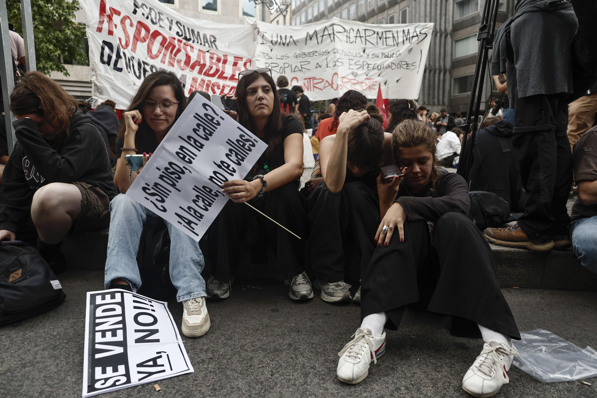 Los manifestantes en el exterior del Congreso de los Diputados siguen en sus móviles la votación de los dos decretos sobre vivienda