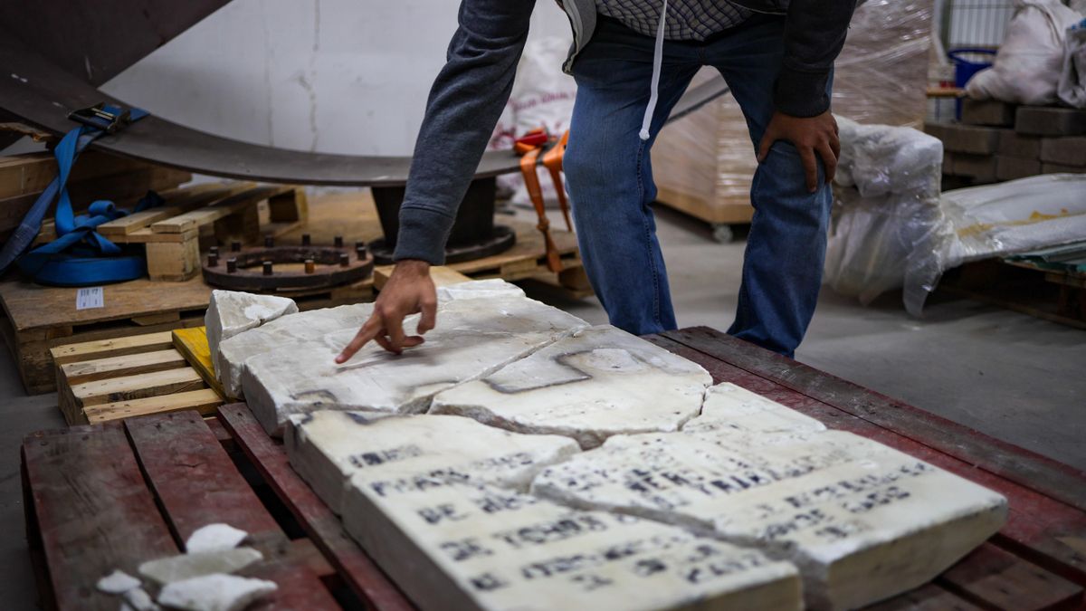 Una persona señala el estado de la placa original en el almacén de Barajas donde se encuentra.