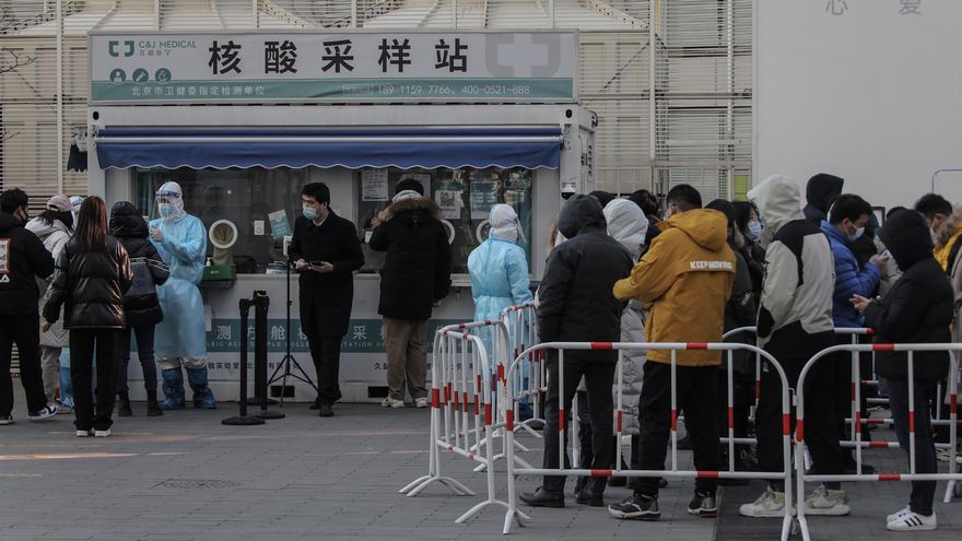 Personas con mascarillas se alinean para realizarse pruebas COVID-19 en Pekín, China.