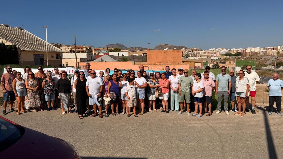 Vecinos afectados junto a la valla que separa sus viviendas del terreno municipal contaminado.